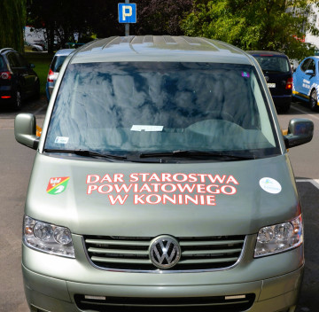 Jasnozielony bus. Na masce są herb i logo powiatu oraz napis dar starostwa powiatowego w koninie.