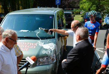 Mężczyzna w okularach oblewa busa szampanem.
