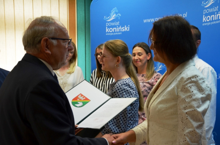 Przewodniczący rady powiatu wręcza nauczycielce dokument potwierdzający awans.