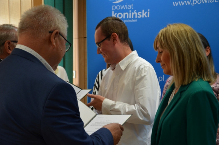 Nauczycielka i nauczyciel odbierają dokumenty potwierdzające awans.