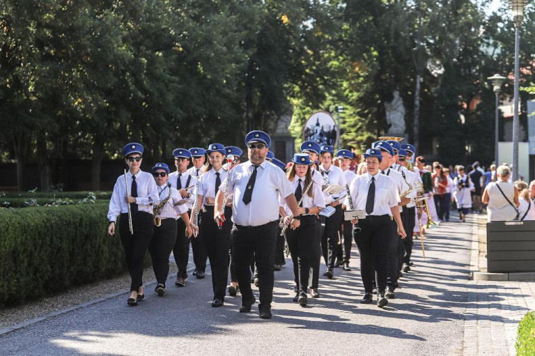 Muzycy orkiestry dętej idą w korowodzie niosąc instrumenty.