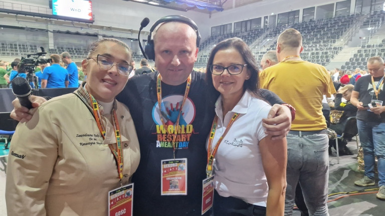 Hala. Mężczyzna stoi między dwiema kobietami. Uśmiechają się do zdjęcia.