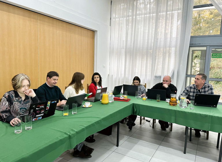 Uczestnicy szkolenia siedzą przed laptopami.