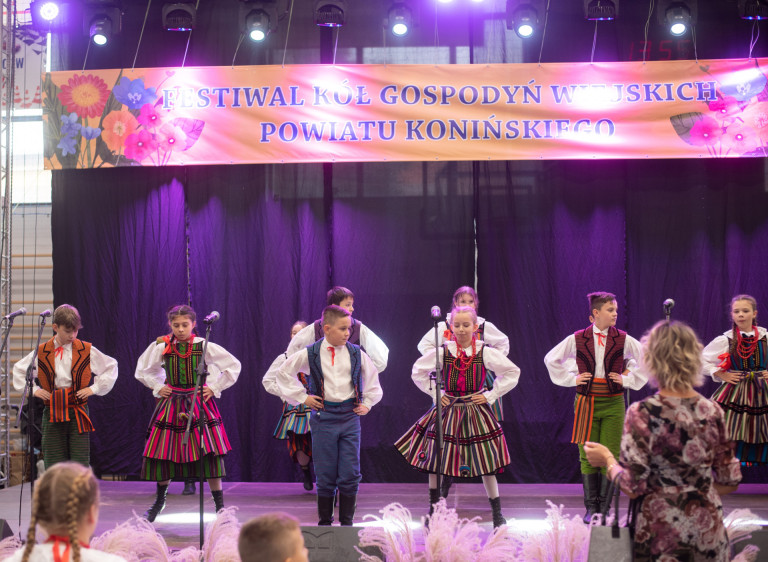 Grupa dzieci w strojach ludowych występuje na scenie.