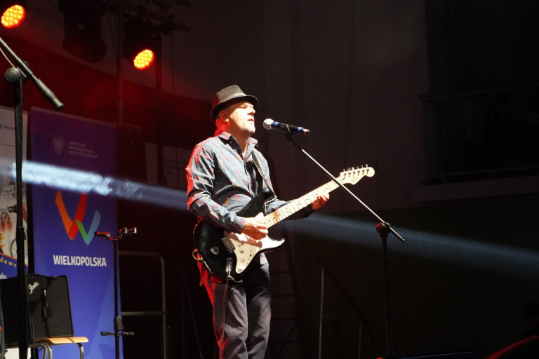 Mężczyzna gra na gitarze na scenie.