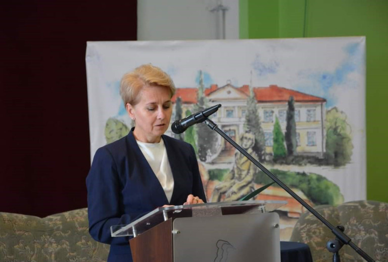 Kobieta w granatowej marynarce przemawia do mikrofonu.