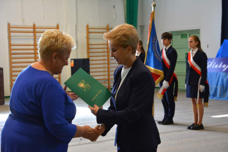Kobieta wręcza dokument drugiej kobiecie.