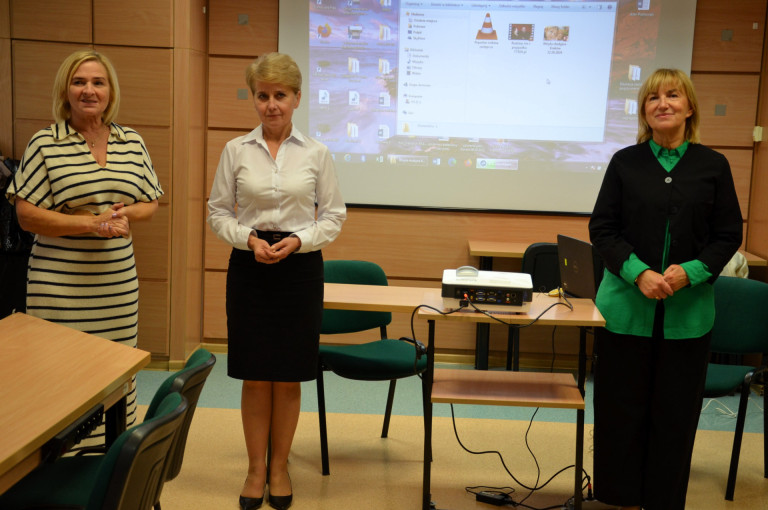 Trzy kobiety stoją na tle ekranu projektora.