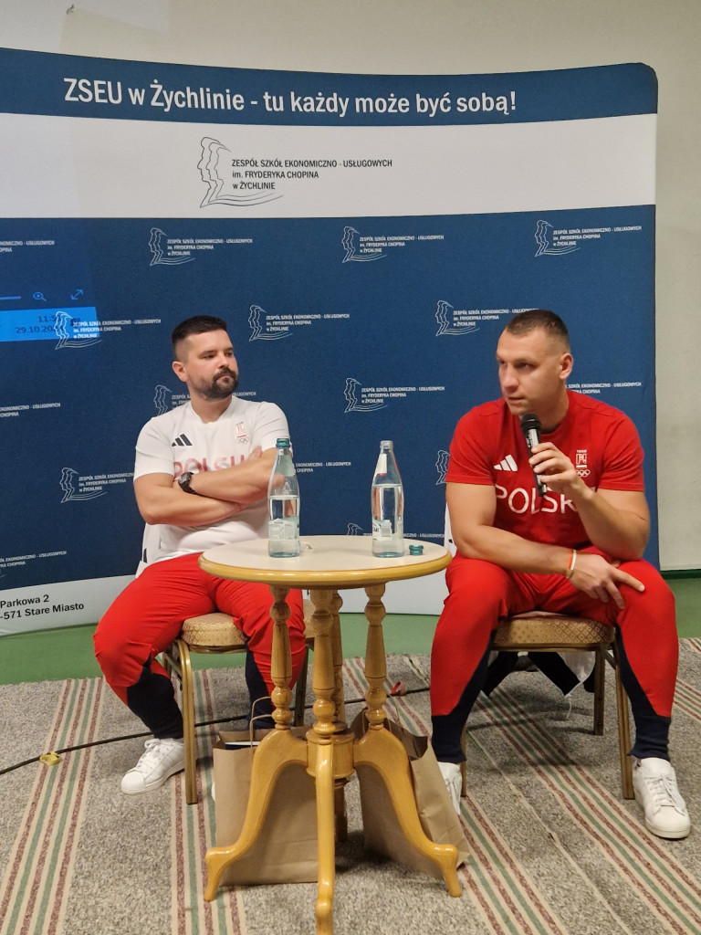 Dwóch mężczyzn w sportowych strojach siedzi przy stoliku.