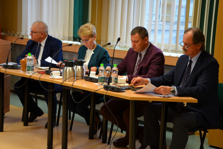 Trzech mężczyzn i kobieta siedzą przy stole.