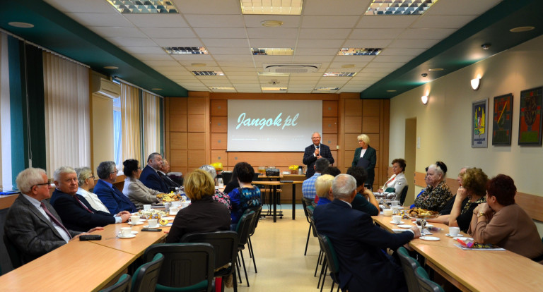 Grupa ludzi siedzi przy stołach w sali konferencyjnej.