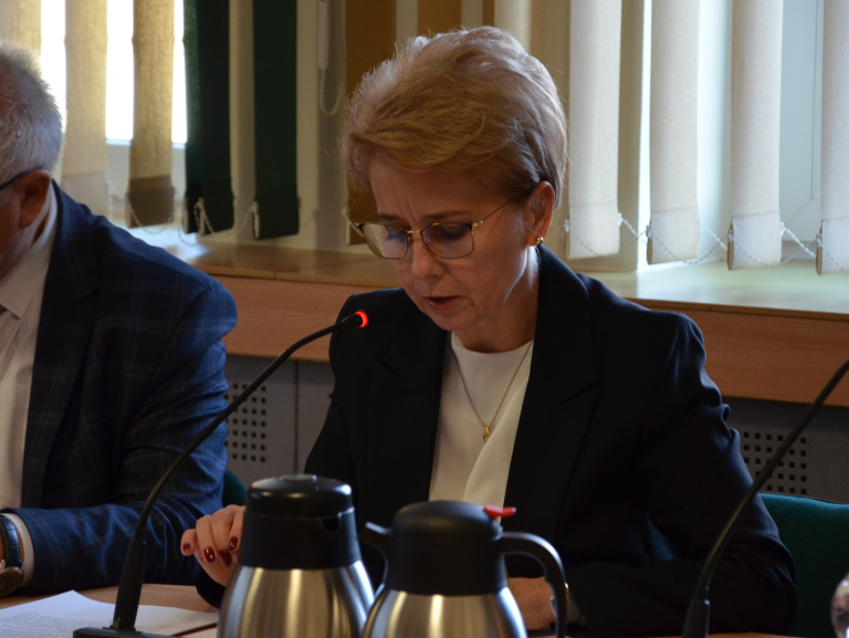 Kobieta w granatowej marynarce przemawia do mikrofonu.