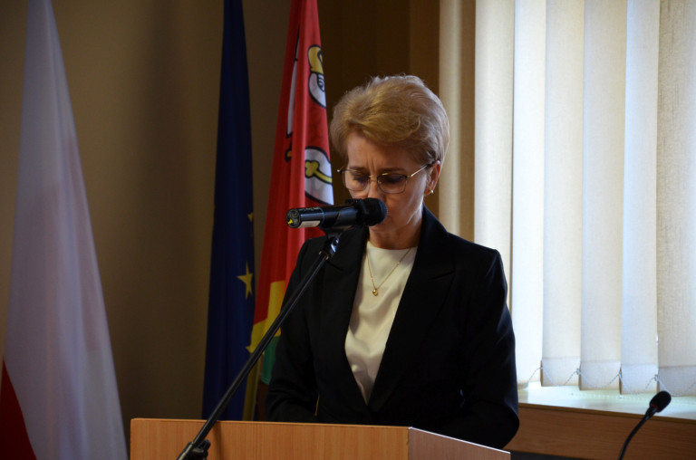 Kobieta przemawia do mikrofonu na mównicy.