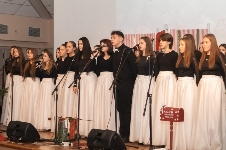 Grupa ludzi ubranych na czarno oraz biało występuje na scenie.