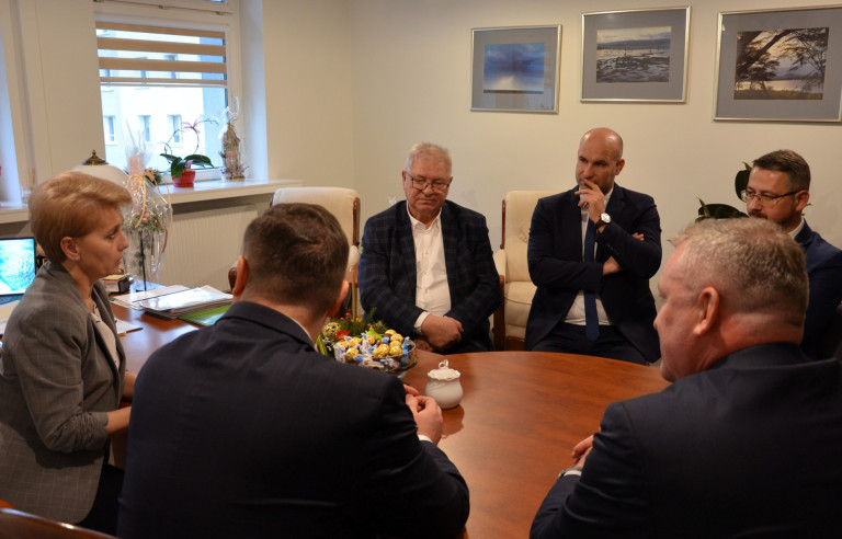 Grupa mężczyzn oraz kobieta siedzą przy stole.
