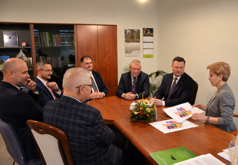 Grupa mężczyzn oraz kobieta siedzą przy stole.