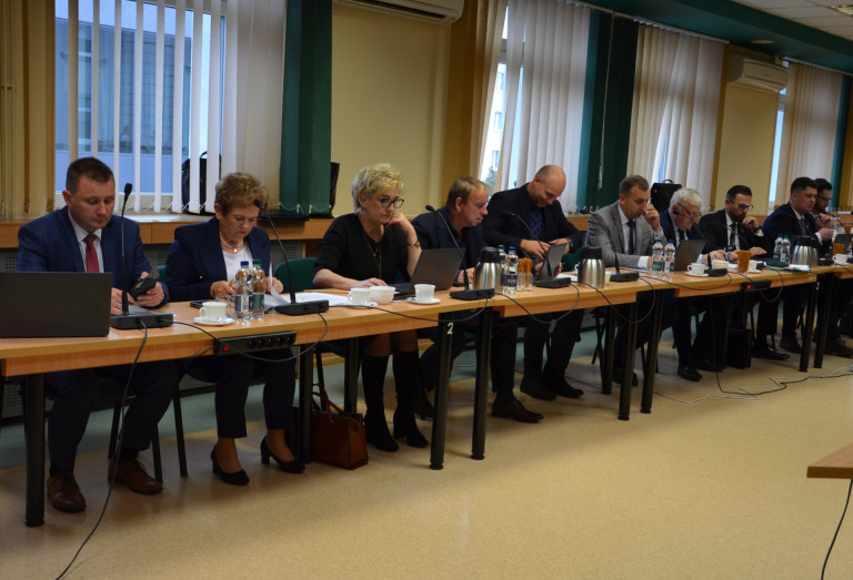 Grupa ludzi siedzi przy stołach w sali konferencyjnej.