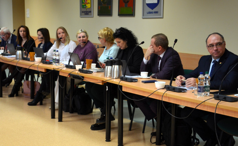 Grupa ludzi siedzi przy stołach w sali konferencyjnej.