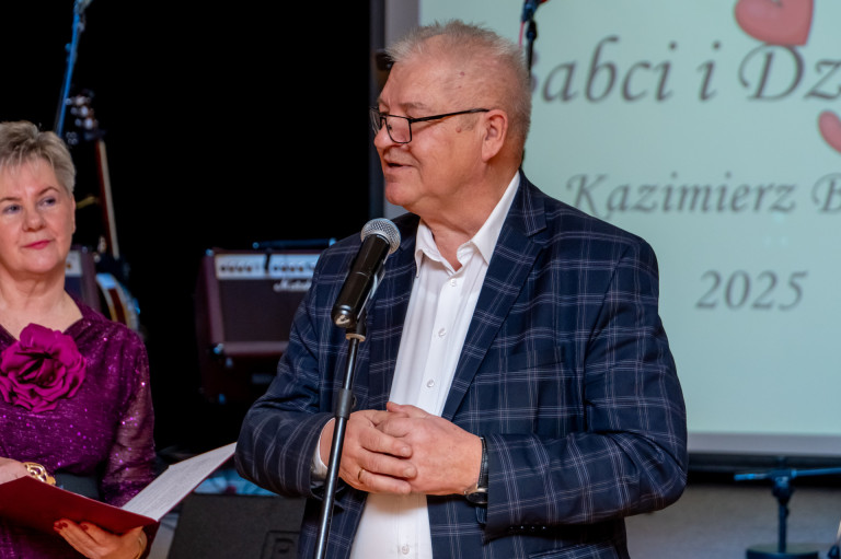 Mężczyzna w granatowej marynarce przemawia do mikrofonu.