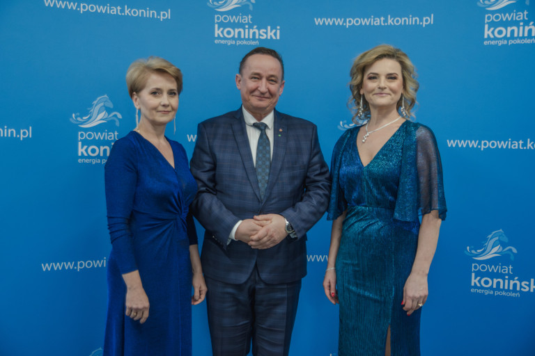 Dwie kobiety stoją obok mężczyzny w garniturze.