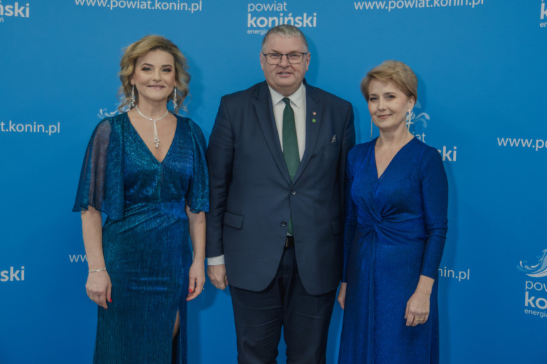 Dwie kobiety stoją obok mężczyzny w garniturze.