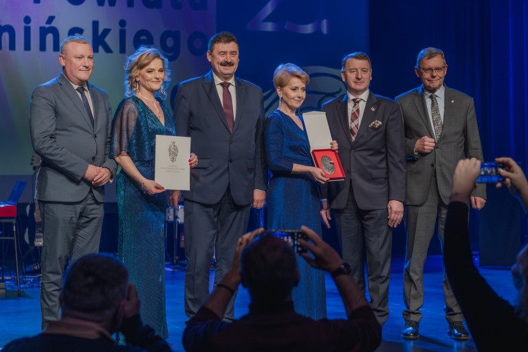 Dwie kobiety i czterech mężczyzn stoją na scenie.