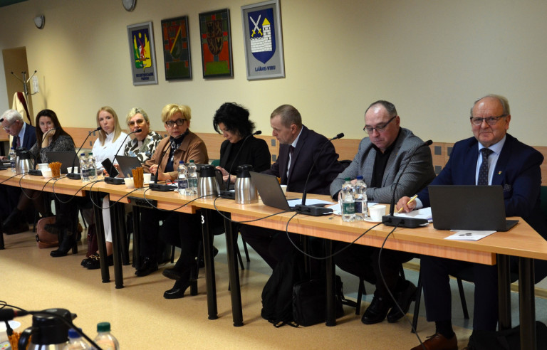 Grupa ludzi siedzi przy stole w sali konferencyjnej.