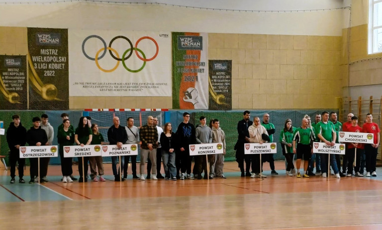Reprezentanci różnych powiatów stoją w sali gimnastycznej.