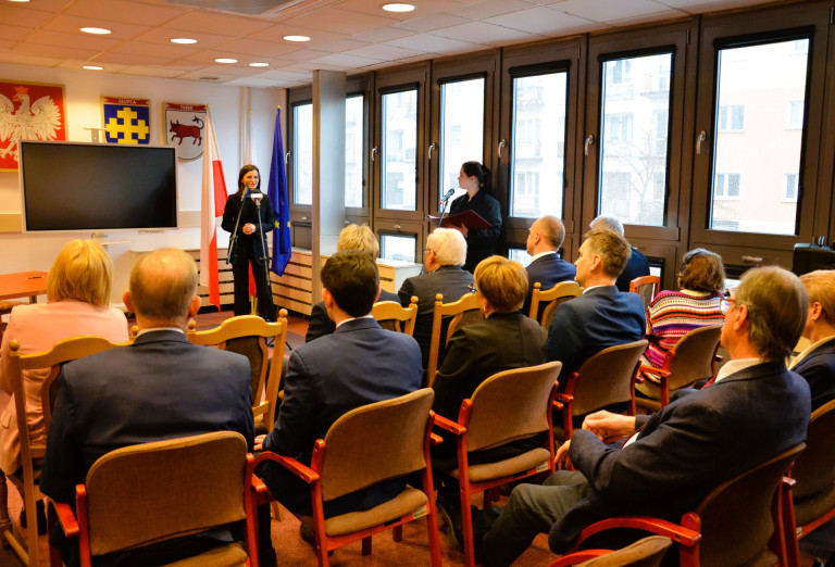 Dwie kobiety przemawiają przed siedzącymi ludźmi w sali konferencyjnej.