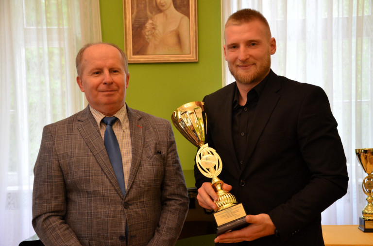 Dwóch mężczyzn. Jeden z nich trzyma złoty puchar.